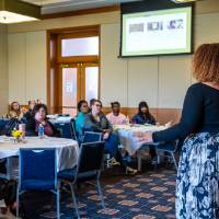 Woman presenting in front of a small room of attendees